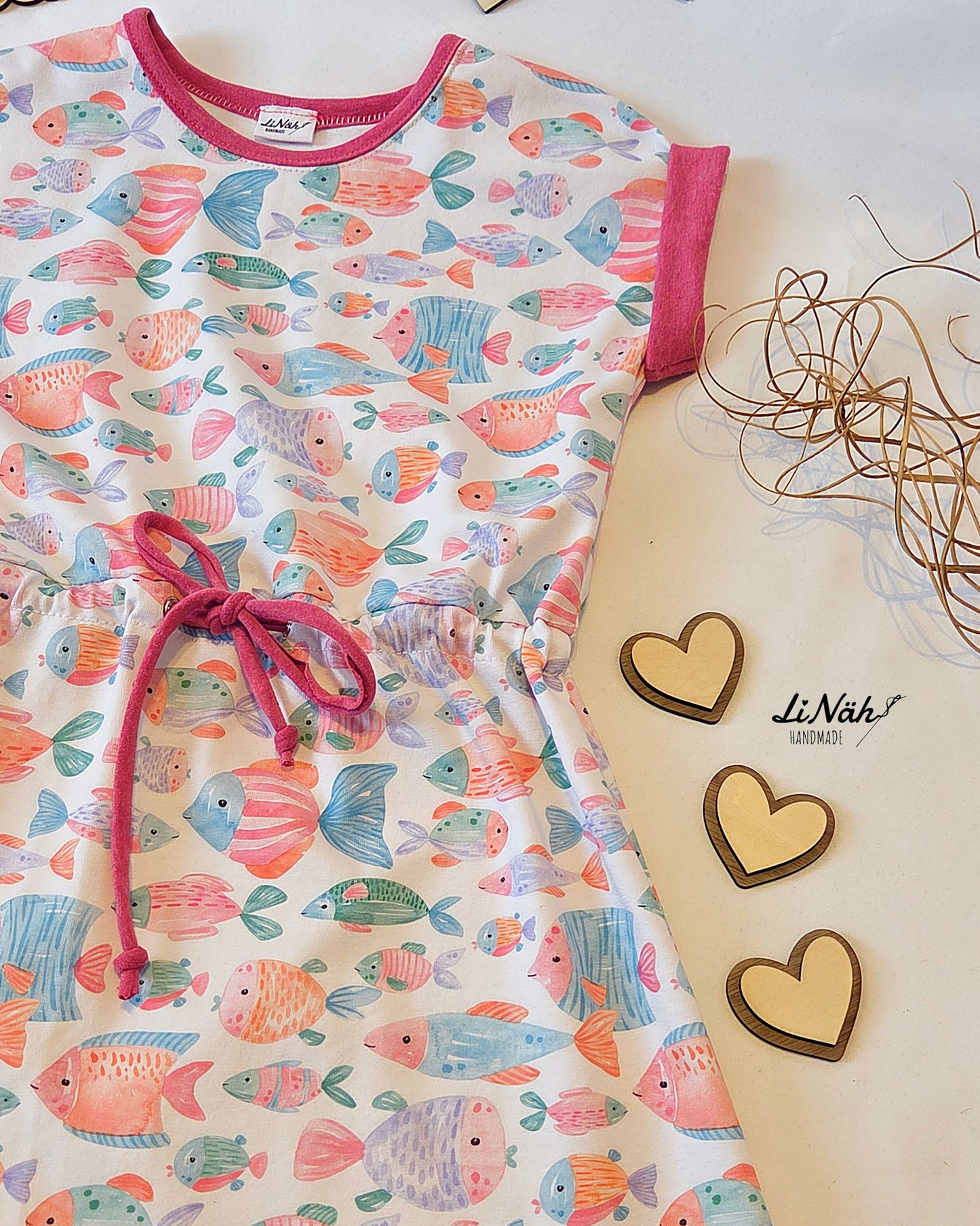 Kinderstoff mit bunten Fischen Fishtales Weiß – selbst genähtes Kinderkleid mit Tunnelzug und pinkfarbenen Bündchen, Aquarellfische auf weißem Jersey. Reaktivdruck Meterware, Öko-Tex Standard 100.