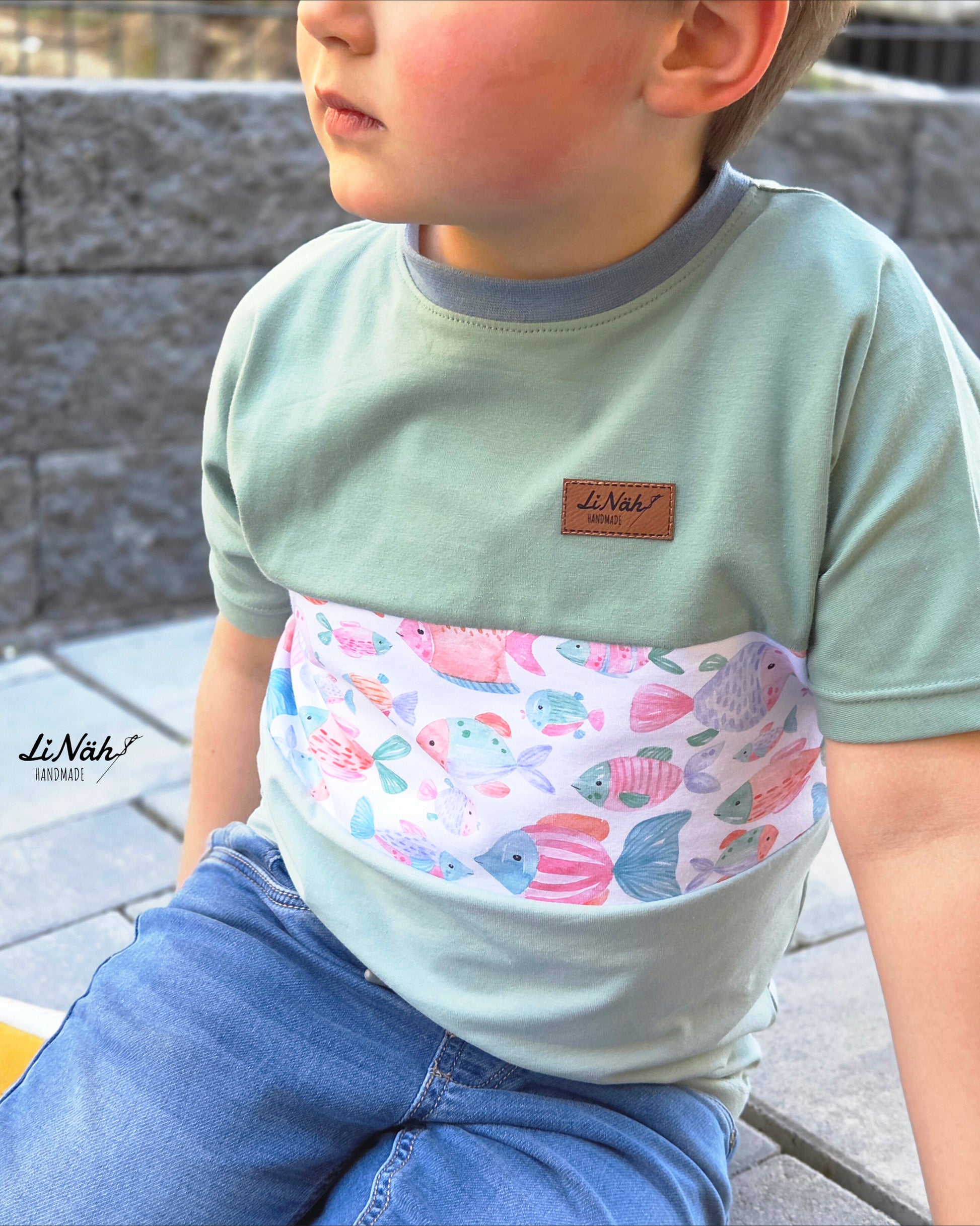 Kinderstoff Fishtales Weiß als Einsatz in einem selbst genähten Kindershirt – Farbblock-Design mit mintfarbenem Uni-Jersey, handgemalte Fische im Brustbereich. Reaktivdruck auf Öko-Tex Standard 100 zertifizierten Stoffqualitäten.