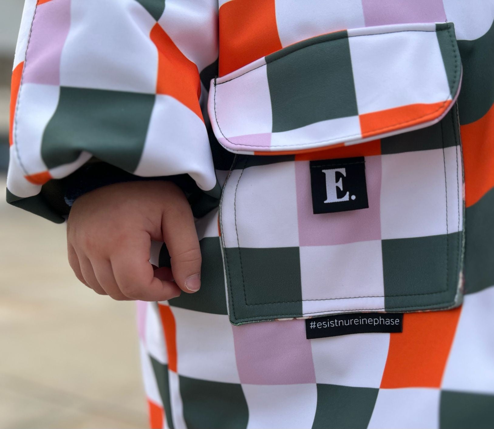 Kombistoff Karo Waldfreunde – Detailaufnahme Pattentasche einer Kinderjacke aus Softshell, Karomuster in Orange, Grün und Flieder. Reaktivdruck auf Öko-Tex Standard 100 zertifizierten Stoffqualitäten.