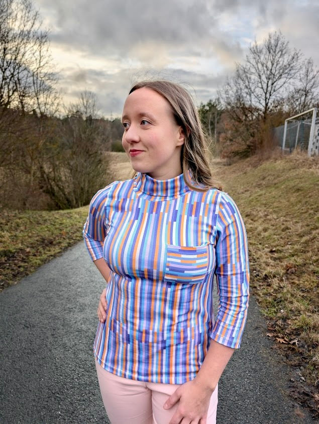 Streifenstoff Happy Stripes genäht als Damen-Rollkragenshirt – Seitenansicht, grafisches Streifenmuster in Blau, Flieder und Orange, Reaktivdruck auf Öko-Tex Standard 100 zertifizierten Stoffqualitäten.
