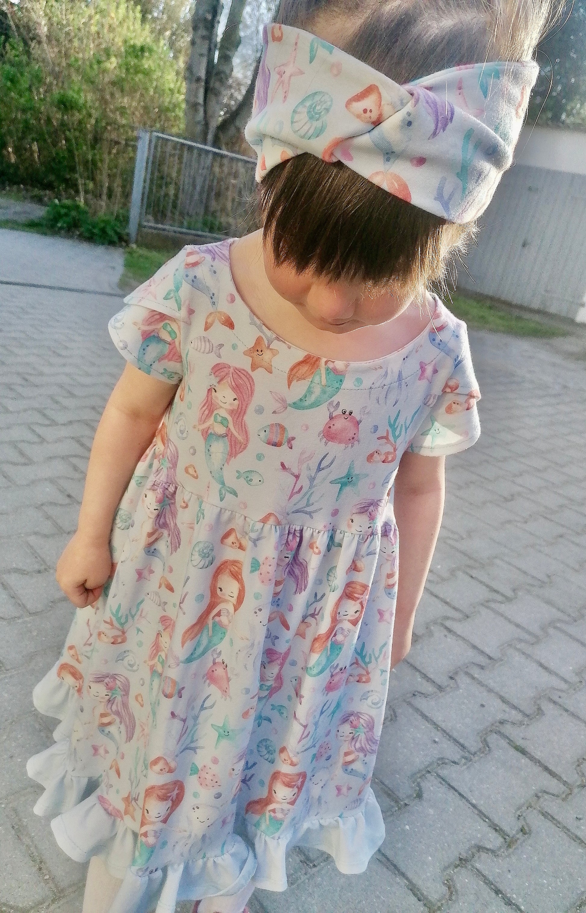 Mädchen im selbstgenähten Drehkleid und Haarband aus Meerjungfrau Stoff für Kinder in Lavendel mit Meerjungfrauen und Unterwassermotiven