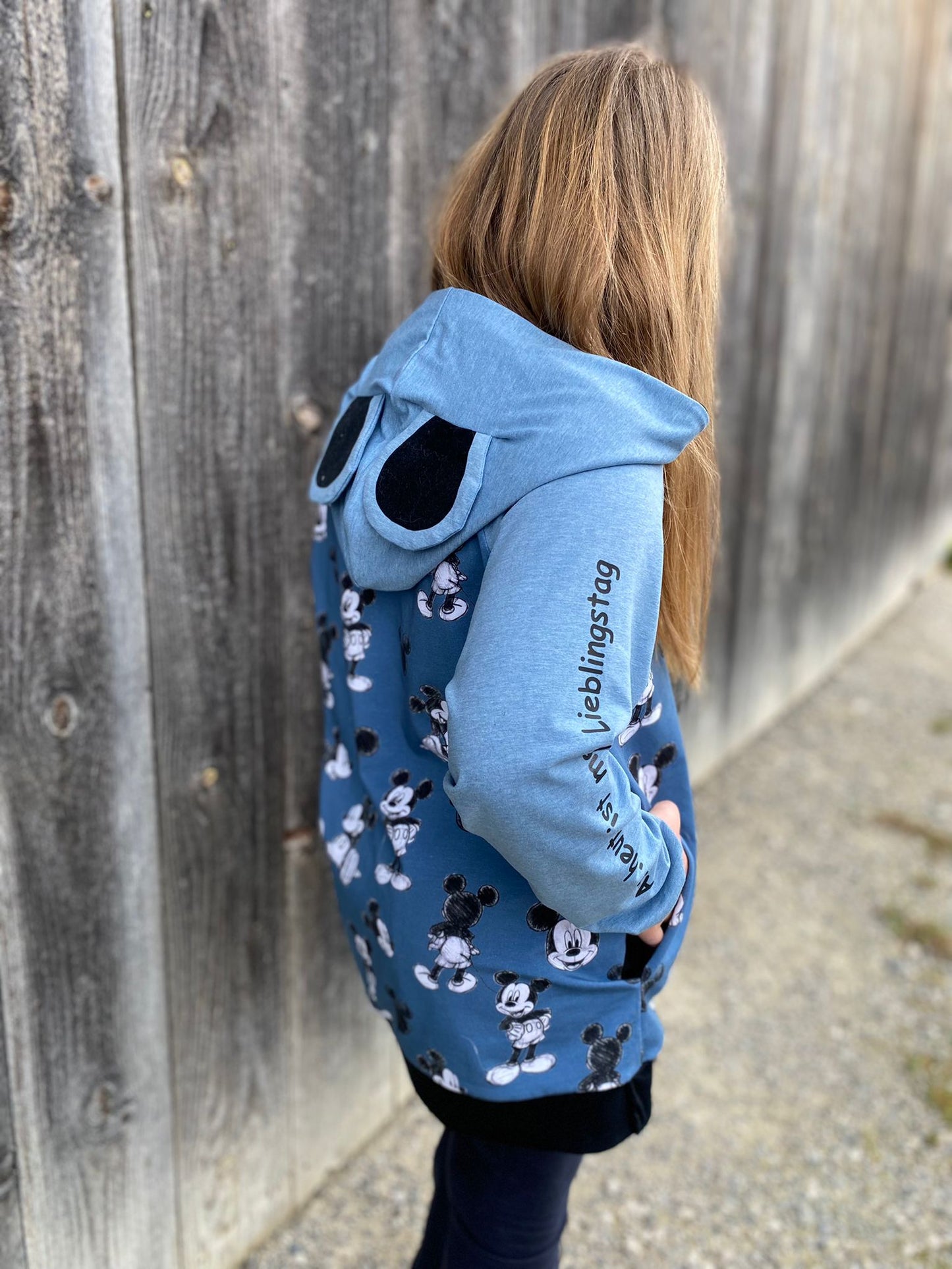 Schnittmuster Hoodie Mika aus blauem Jersey mit Print – Variante mit runden Tierohren auf der Kapuze, Raglan-Schnitt von hinten, Colorblocking mit hellblauem Ärmel