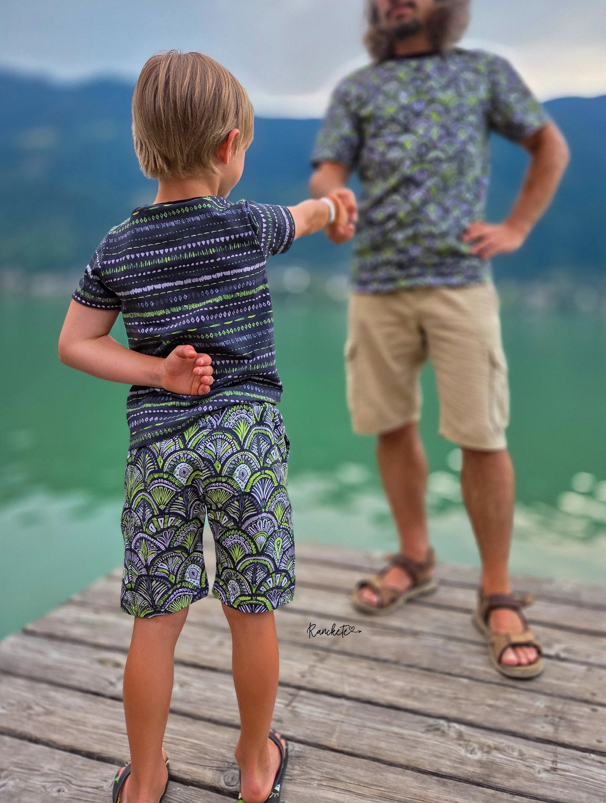 Vater und Sohn tragen beide Shirts aus dem Streifenstoff Grün Schwarz der Kollektion Emerald Reverie.