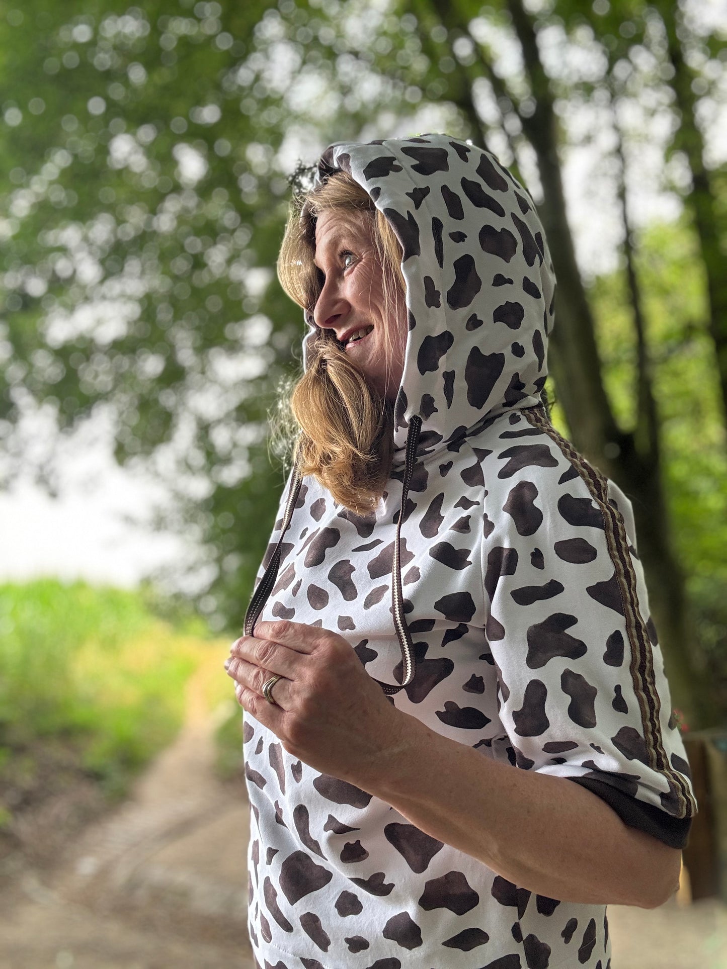 Frau im selbstgenähten Hoodie mit Kapuze aus Cow-Print-Stoff, Design Auf der Weide von HIP SOM HAP