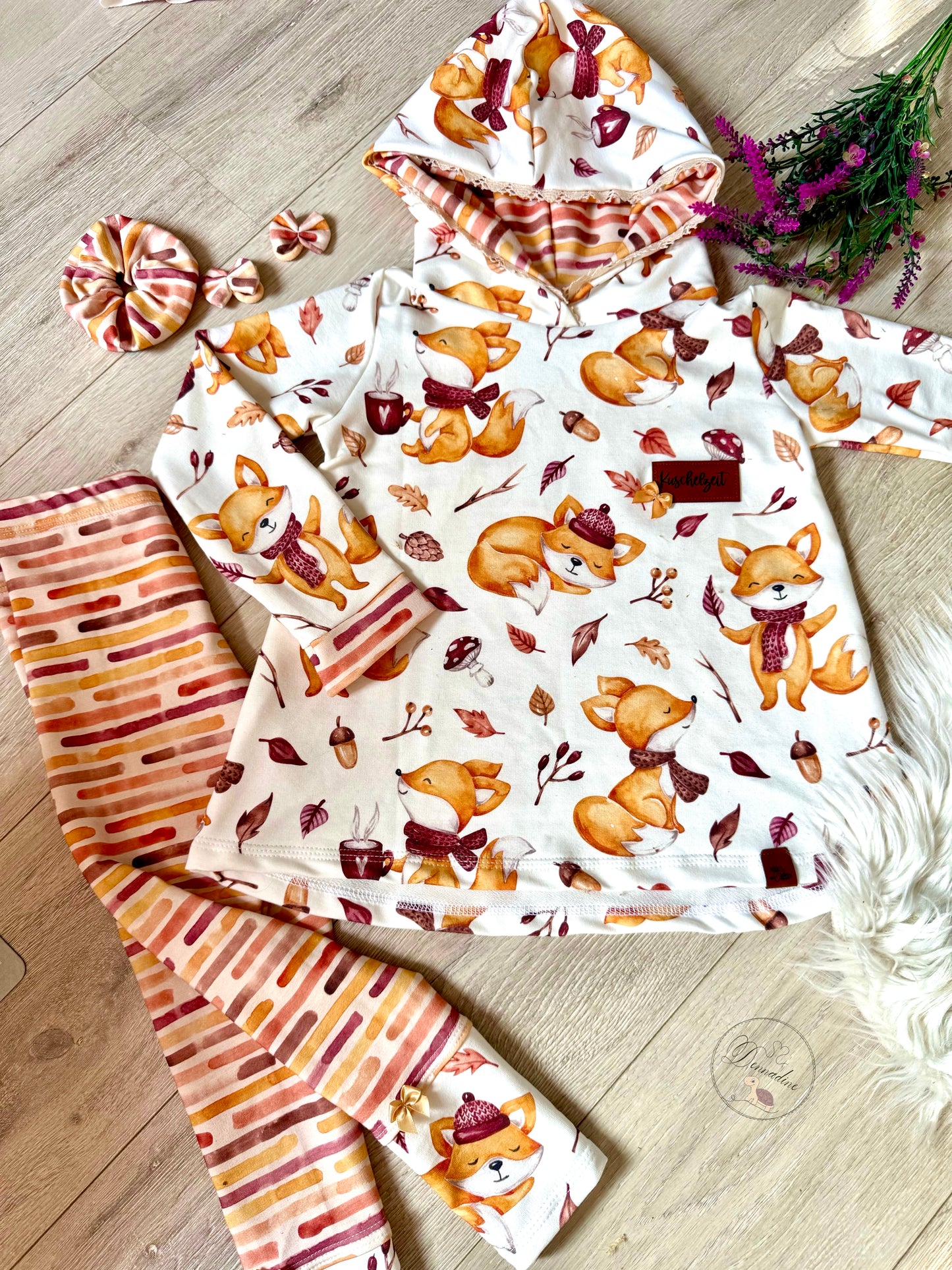 Fertig genähtes Hoodie-Kleid aus Cozy Fox Fuchsstoff Kinder flach ausgelegt neben passendem Streifen-Kombistoff Haarschleife und Scrunchie in warmen Herbsttönen