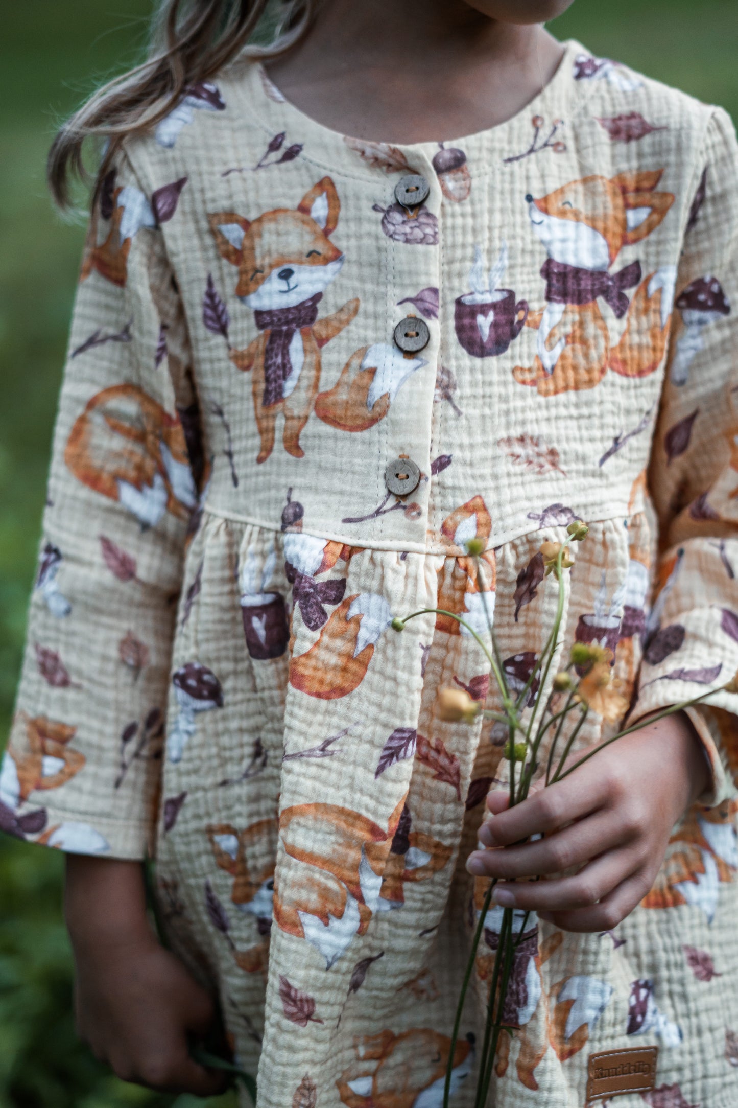 Detailaufnahme Knopfleiste am sandfarbenen Musselinkleid aus Cozy Fox Fuchsstoff Kinder mit Fuchs Kakaotasse und Herbstblättern