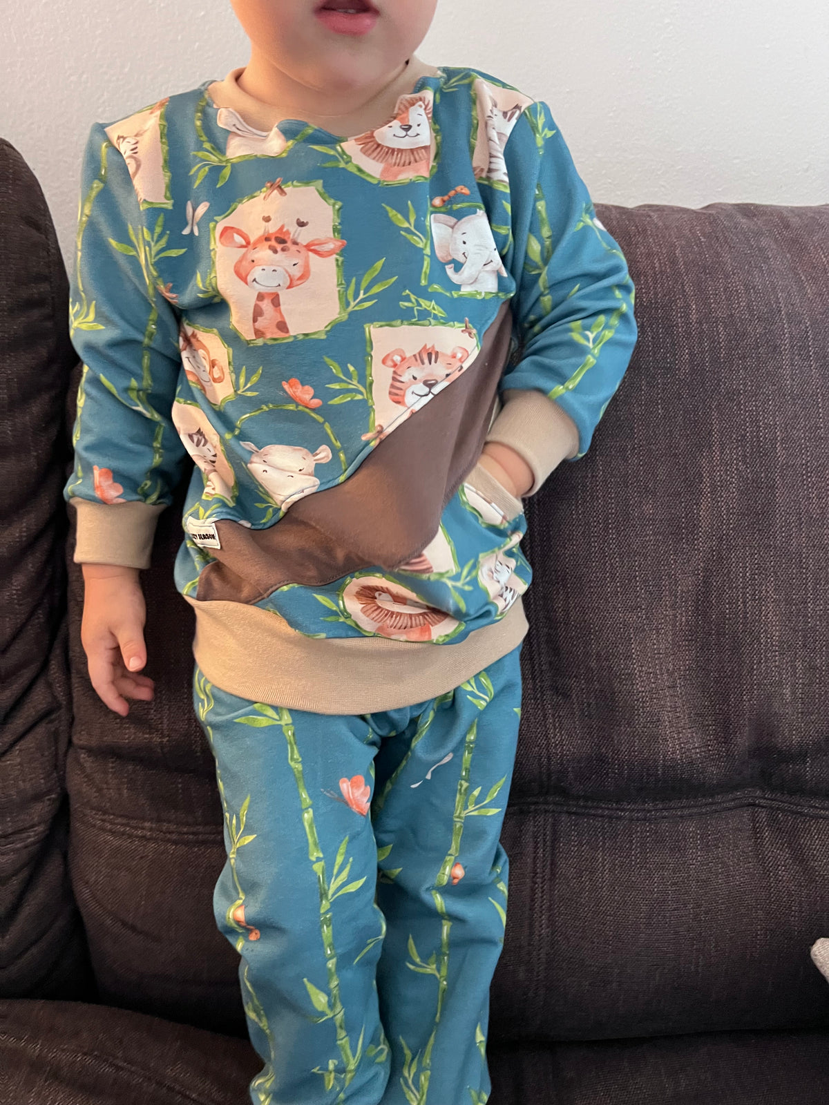 Kind in einem Pullover aus Kinderstoff Hey Safari auf Petrol mit Giraffe, Tiger und Elefant, dazu eine Hose aus dem passenden Bambus-Kombistoff