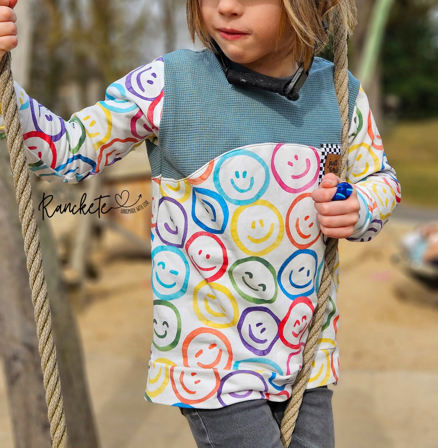 Kind im selbstgenähten Shirt aus Lachgesichter Stoff mit bunten Kreisen, beim Klettern am Seil, Design Kunterbunte Gefühle von HIP SOM HAP